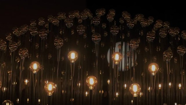 Hundreds of edison vintage retro lightbulbs brighten up darkness in different order and rhythm, perform as symbols of ideas, startup and creativity, new business beginnings