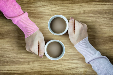 hands holding cups of coffee hot on wooden table background vintage