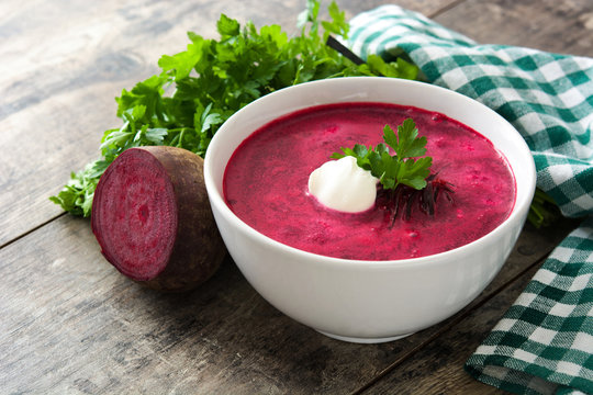 Beet soup in white bowl on wooden table