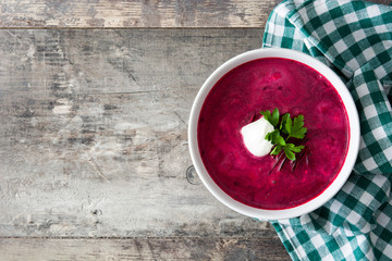 Beet soup in white bowl on wooden table. Top view copyspace