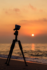 Action Camera Sony X 3000 on a sandy beach shooting a video of sunset over the sea.
