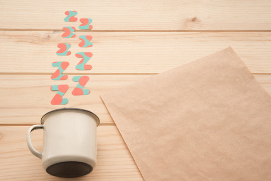 Zetas de papel saliendo de una taza vintage de color beige y un papel  en blanco con espacio para un mensaje sobre una superficie de madera. Concepto: sue&ntilde;o