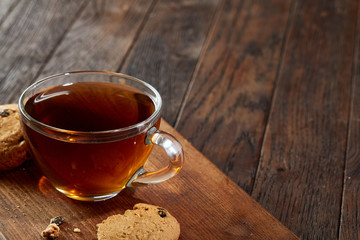 Cup of tea with cookies on a cutting board on a wooden background, top view