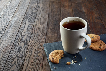 Cup of tea with cookies, workbook and a pencil on a wooden background, top view