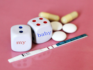 Pregnancy test positive with two stripes and contraceptive pill. The dice on pink background.