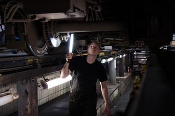 Obraz na płótnie Canvas Mechanic using light to inspect a subway car