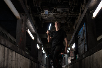 Mechanic using light to inspect a subway car