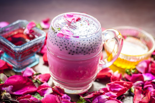 Indian/Asian popular summer drink i.e. Gulab Shake or Rose shake consisting of milk,rose syrup,sugar and honey with sabja seeds or sweet basil seeds in a transparent glass,with all ingredients.