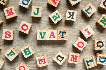 Letter block in word VAT (Abberviation of Value added tax) with another on wood background
