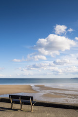 Empty bench seat looking out to sandy beach