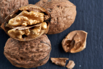 Top view close-up shot of cracked walnuts on dark background, shallow depth of field, macro