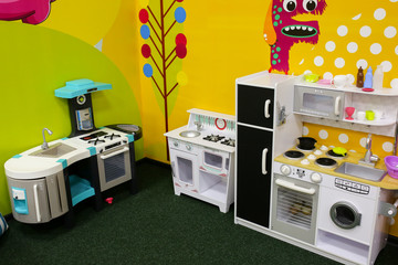 White and yellow toy kitchens. Games for girls in the entertainment center or in the house. Children free time. Retro play kitchen in vintage and modern styles. Cooking for kids. Bright wallpaper