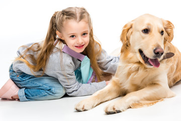 Closeup view of smiling little kid with lying beige dog isolated on white