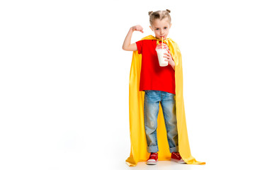 Supergirl in yellow cape drinking milkshake and showing muscles on hand isolated on white