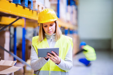 Woman warehouse worker with tablet.