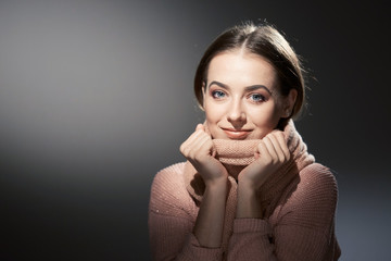 beautiful girl in pink knitted sweater. emotional portrait on a dark background.