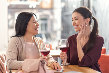 Favourite drink. Delighted positive young woman holding glasses and enjoying wine while