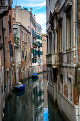 Fototapeta na wymiar An old canal in Venice with boats parked near entrances of residential buildings