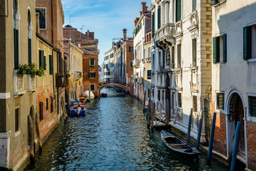 Fototapeta na wymiar An old canal in Venice with boats parked near entrances of residential buildings