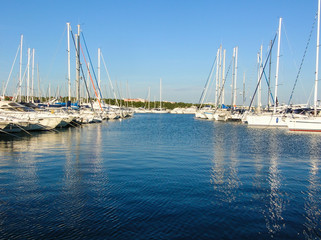 Fototapeta premium Boating Lifestyle. Boats docked in a marina with a rocky foreground and the beginning of a sunset in the background.