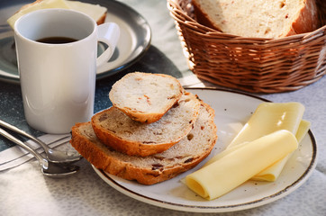 Breakfast with a cup of black coffee, homemade crusty bread and thin cheese slices