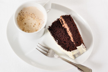 Cup of coffee with one piece chocolate cake and dessert fork on white background