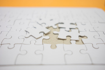 business background white jigsaw placed on orange table with copy space. image for texture, problem, thinking, idea, toy, success, game concept