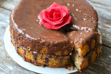 Handmade sponge cake with chocolate frosting. Small cake with cacao ganache glaze. Red sugar rose decorated. Homt pastry. Sweet dessert. Cute birthday cake present.