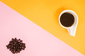 top view. beverage background cup with coffee and coffee beans placed on yellow and pink table. image for copy space, food, drink, isolated, cafe, business concept