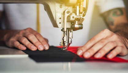 Close-up man hands sewing fabric on sewing machine