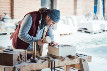 Steinmetz bearbeitet Sandstein in seiner Werkstatt
