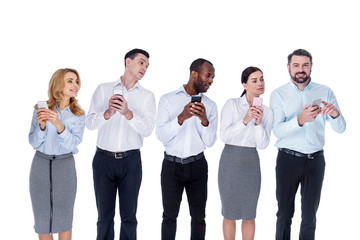 So curious. Handsome content bearded young man smiling and showing a new post to his curious colleagues and his co-workers standing with their phones