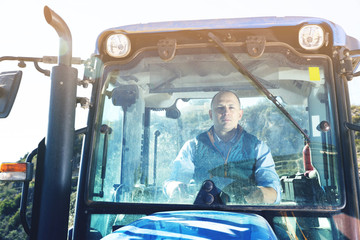Portrait of confident male owner of vineyard behind glass in tractor cab