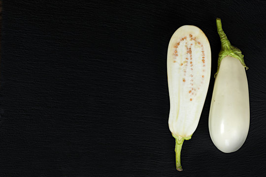 White slice eggplant on black stone surface. Top view, copy space.