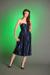 Girl in dark blue dress in studio on green background