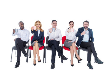 Lunch time. Attractive exuberant stylish young co-workers smiling and drinking coffee and sitting on the chairs