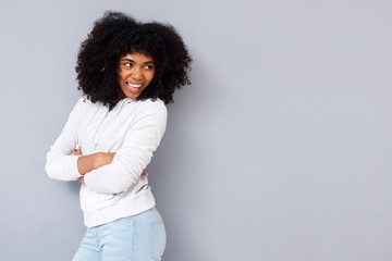 Attractive african woman standing with her arms crossed and smiling against gray background