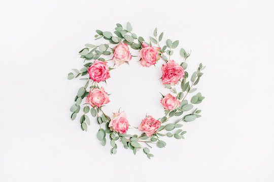 Floral frame wreath of red rose flowers and eucalyptus branches on white background. Flat lay, top view floral mockup with empty space.