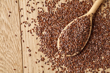 Wooden spoon with flax seeds on rustic background, top view, close-up, shallow depth of field, selective focus