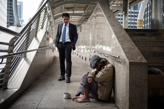 Business man look at Homeless in city