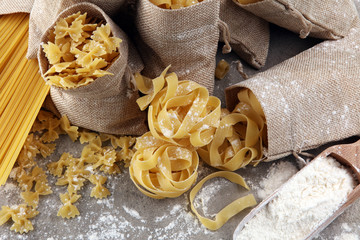 Various mix of pasta on grey rustic background. Diet and food concept.