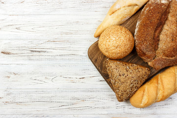 Assortment of fresh bread on a white wooden background. top view with copy space