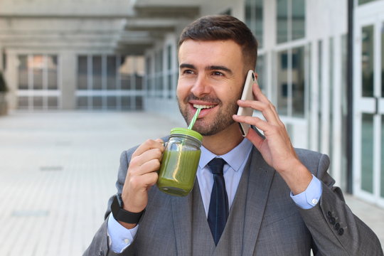 Healthy businessman drinking juice while working