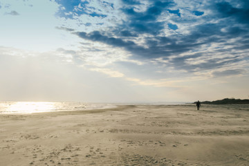 Fototapeta na wymiar A man walking alone on a winter beach