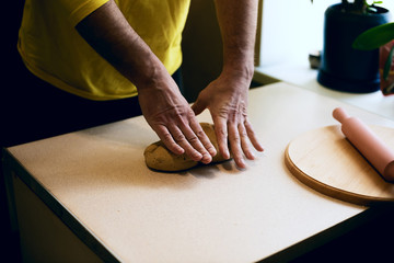 Obraz na płótnie Canvas Male hands knead the dough on the white table, top view