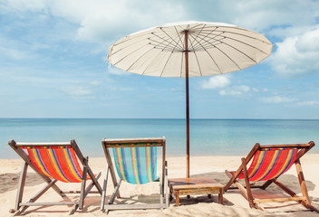 beach lounge chairs under umbrella on beach.