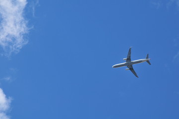 Passenger airplane flying under cloudy blue sky