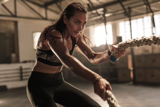 Fitness woman using battle ropes for exercising