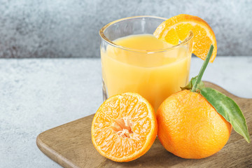 Fresh orange tangerines and juice glass on cutting board