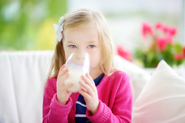 Cute little girl drinking fresh organic milk at sunny summer day